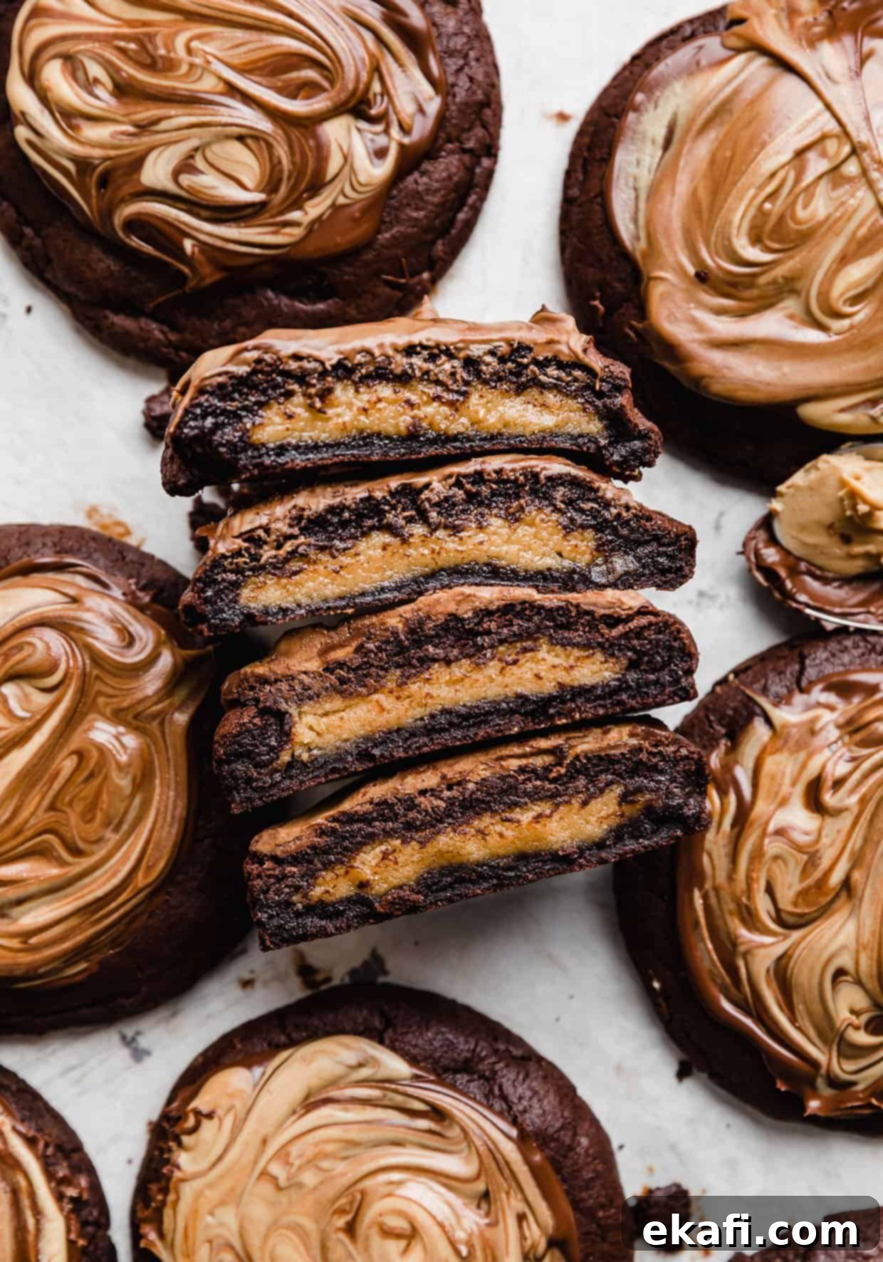 Μπισκότα με φυστικοβούτυρο και καφέ brownie Crumbl 3 Μπισκότα Crumbl Peanut Butter Brownie κομμένα στη μέση, δείχνοντας το μπισκότο φυστικοβούτυρου στο κέντρο.
