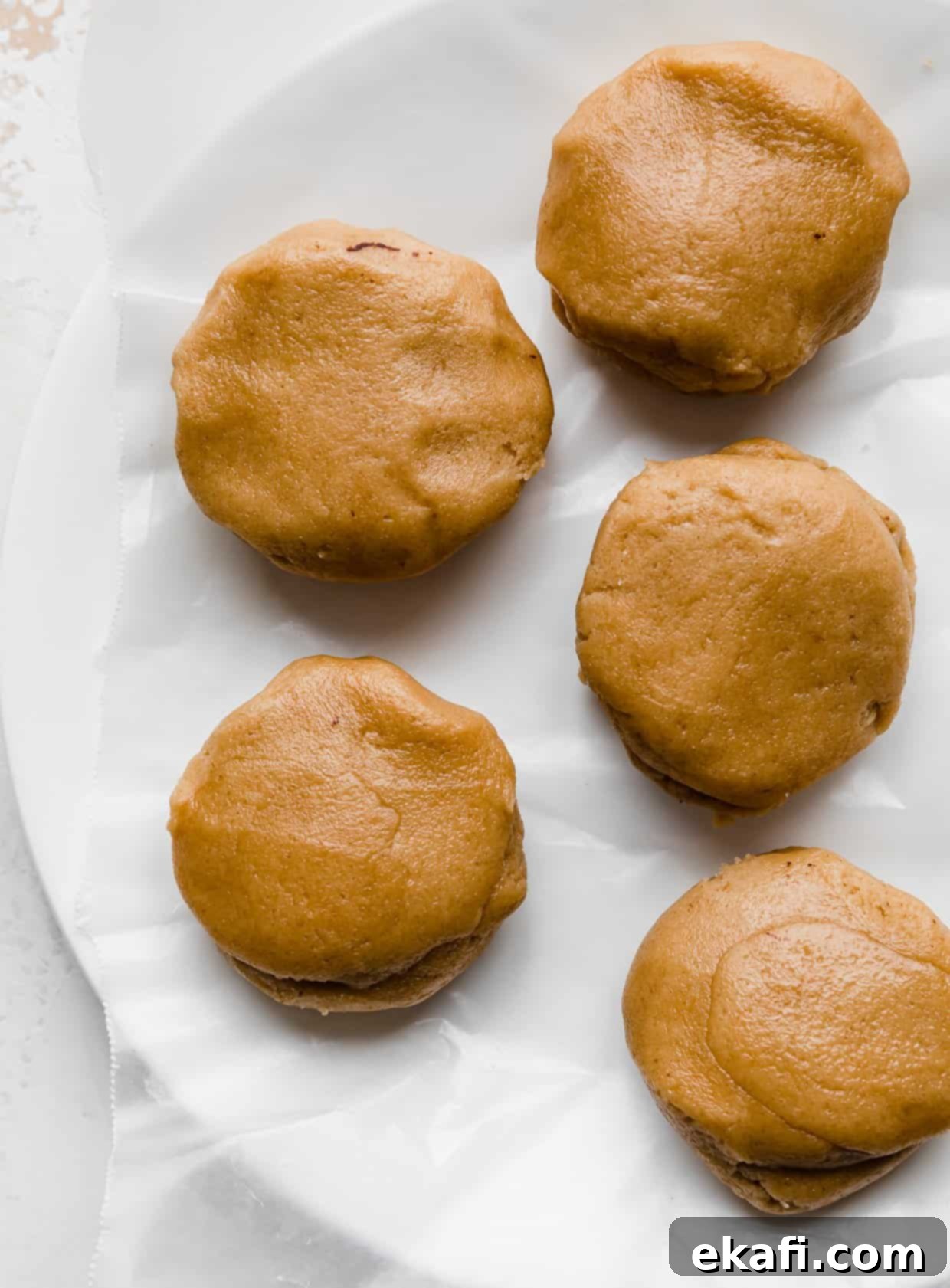 Μπισκότα με φυστικοβούτυρο και καφέ brownie Crumbl 4 Μπάλες ζύμης μπισκότου φυστικοβούτυρου σε ένα λευκό πιάτο.