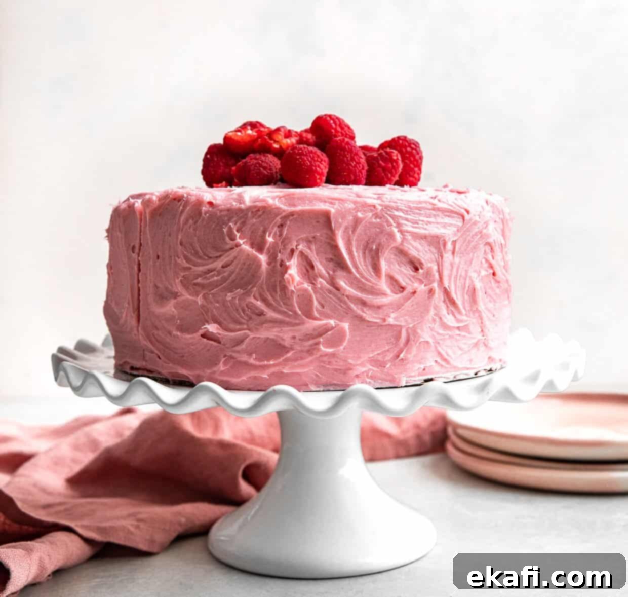 Perfect Lemon Raspberry Cake 11 A two layer Lemon Raspberry Cake frosted with pink frosting on a white cake stand.