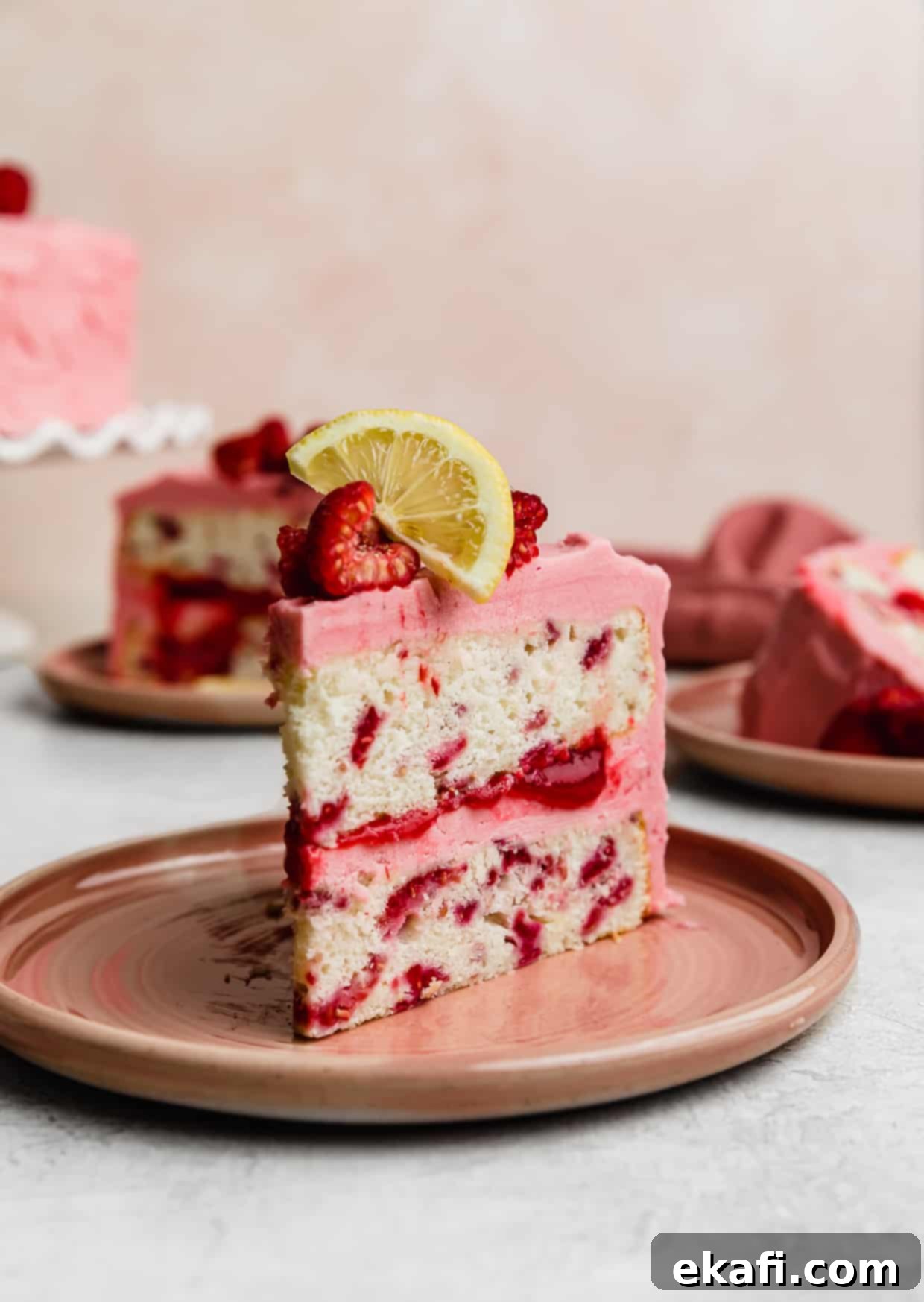 Perfect Lemon Raspberry Cake 3 A slice of Lemon Raspberry Cake on a pink plate against a light pink background.