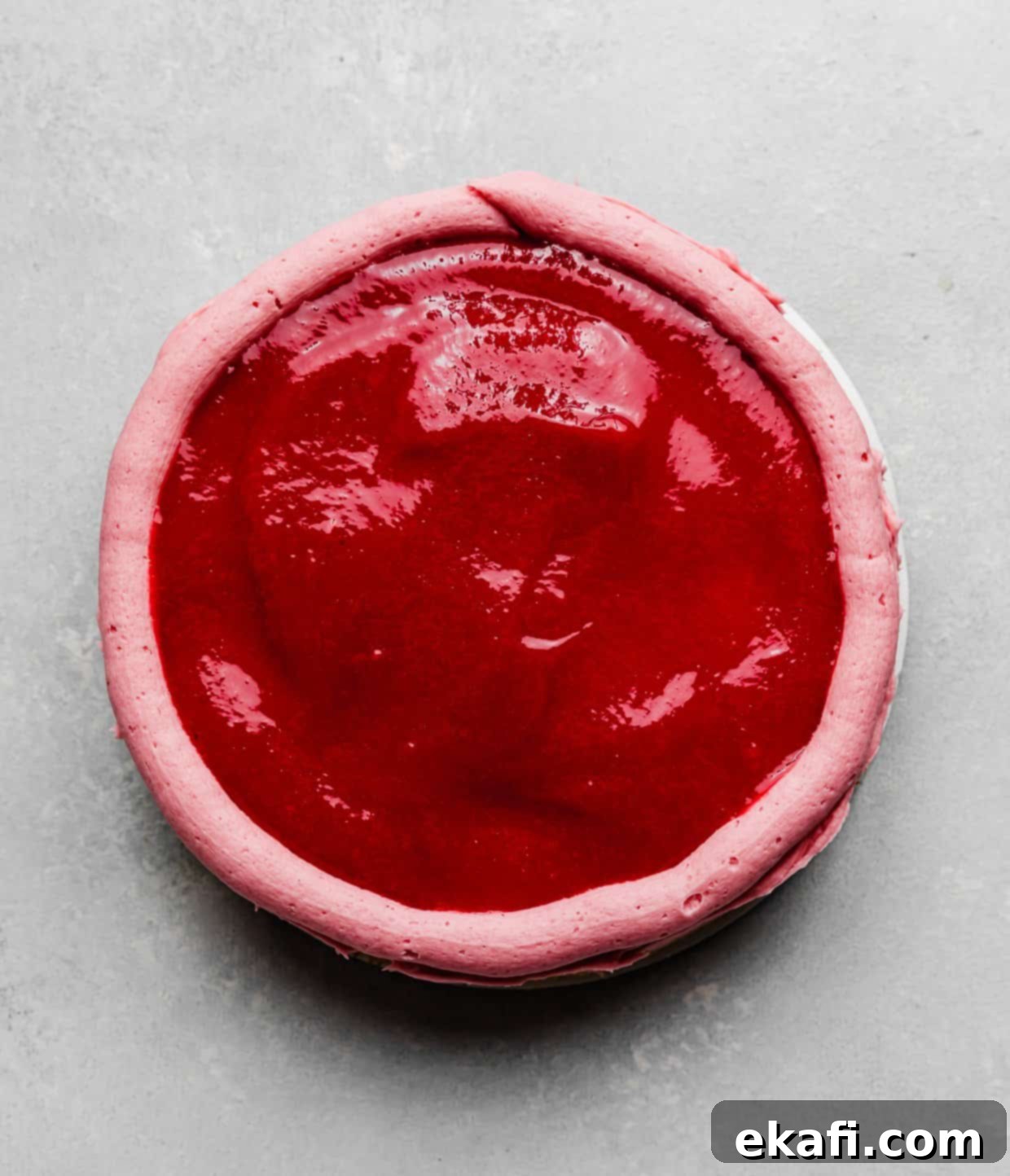 Perfect Lemon Raspberry Cake 9 Overhead photo of a raspberry sauce overtop a round cake layer.