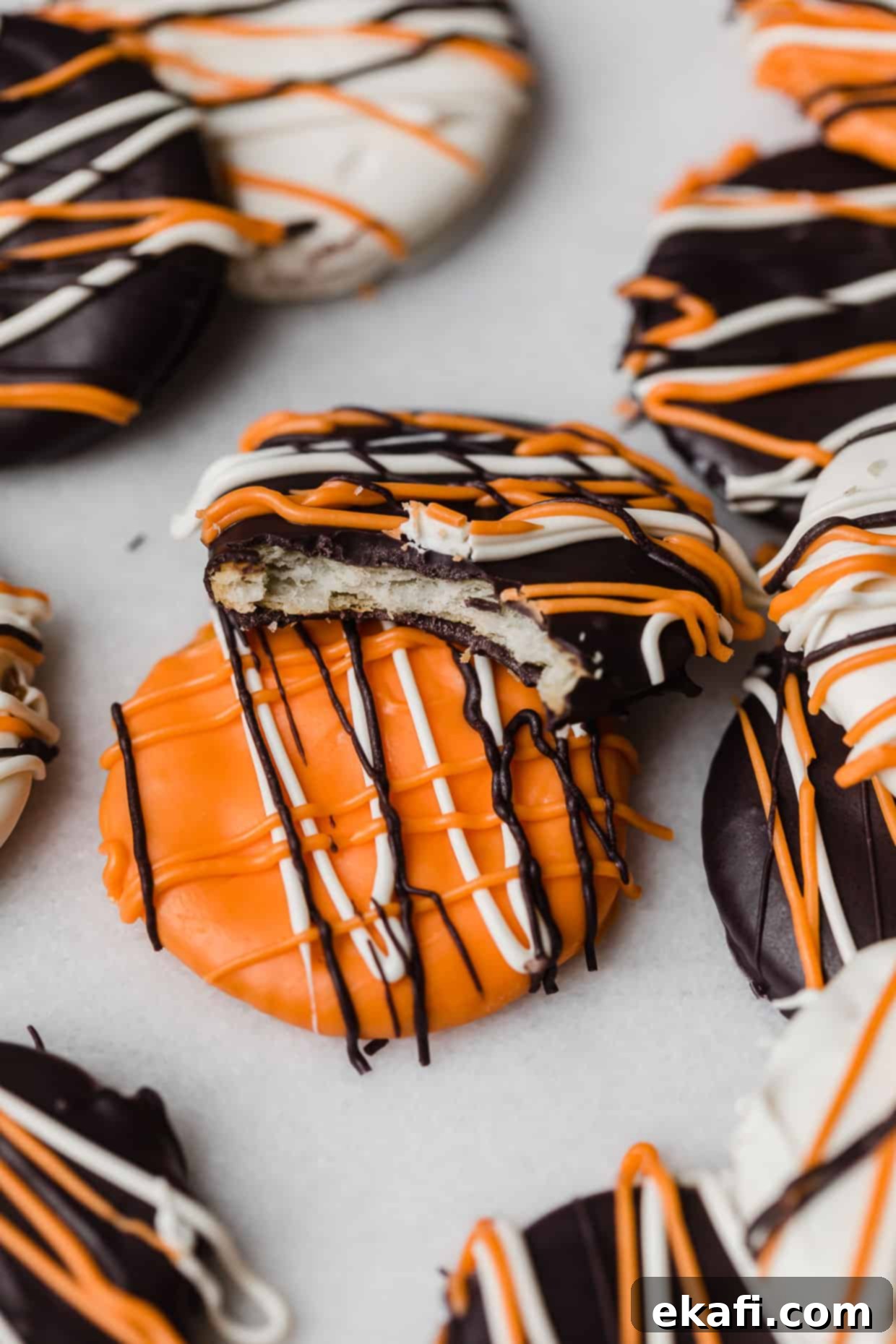 Haunted Snaps 11 A bite taken out of a Halloween Cracker that's covered with black, orange, and white melted chocolate, showcasing the delicious layers.