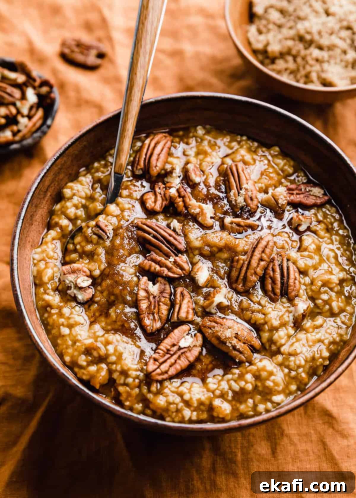 Autumn Pumpkin Spice Steel Cut Oats 2 A beautifully presented bowl of Pumpkin Steel Cut Oats on an inviting orange background, garnished with a sprinkle of cinnamon and a few chopped pecans, evoking a cozy autumn morning feel.