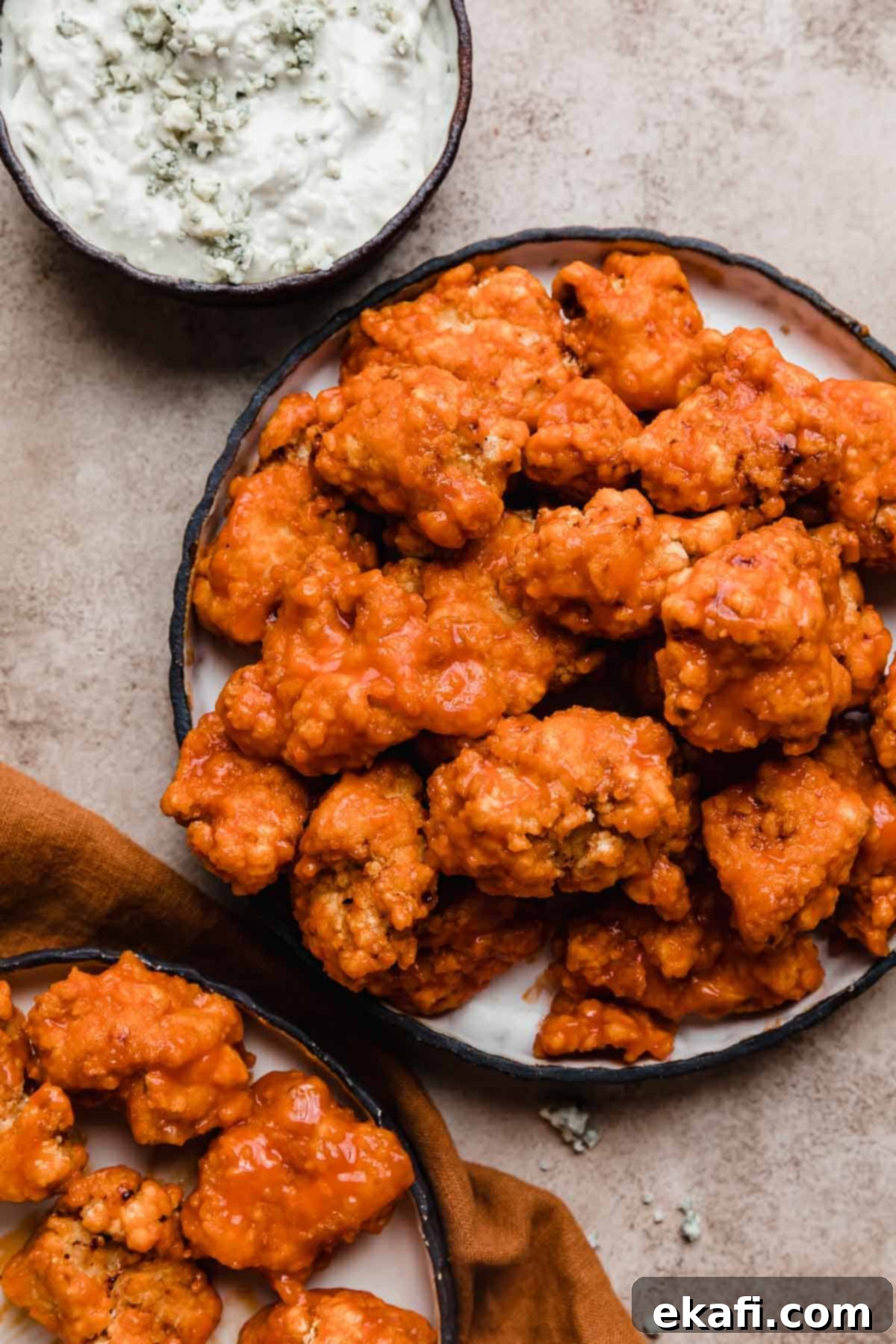 Fiery Buffalo Chicken Poppers 2 Overhead photo of Buffalo Chicken Bites on a black lined plate on a beige background, with a side of blue cheese dip.