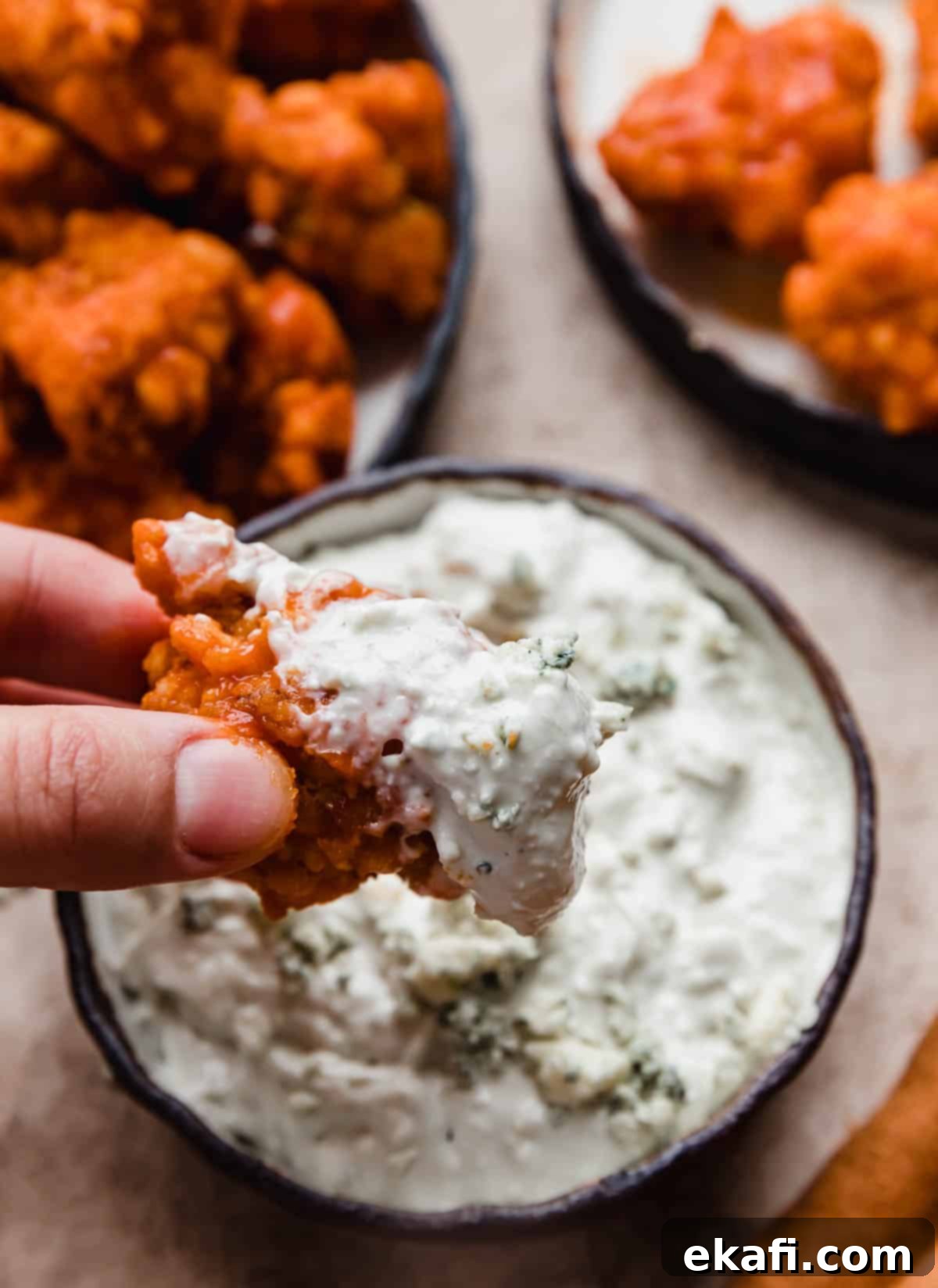 Fiery Buffalo Chicken Poppers 9 A Buffalo Chicken Bite dipped in blue cheese sauce, showing the crispy coating and creamy dip.