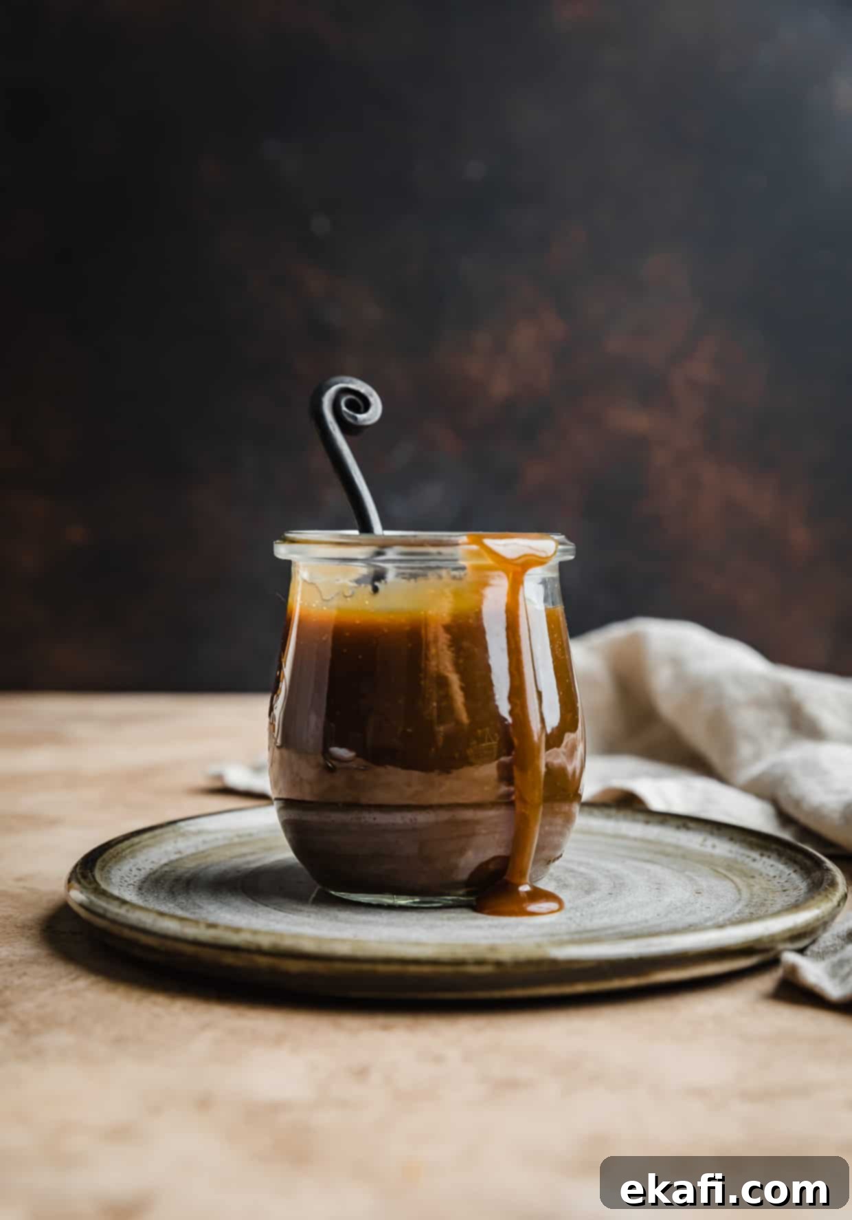 Salted Butterscotch Sauce 8 Homemade butterscotch recipe in a glass jar, perfectly smooth and ready to be served against a warm brown background.