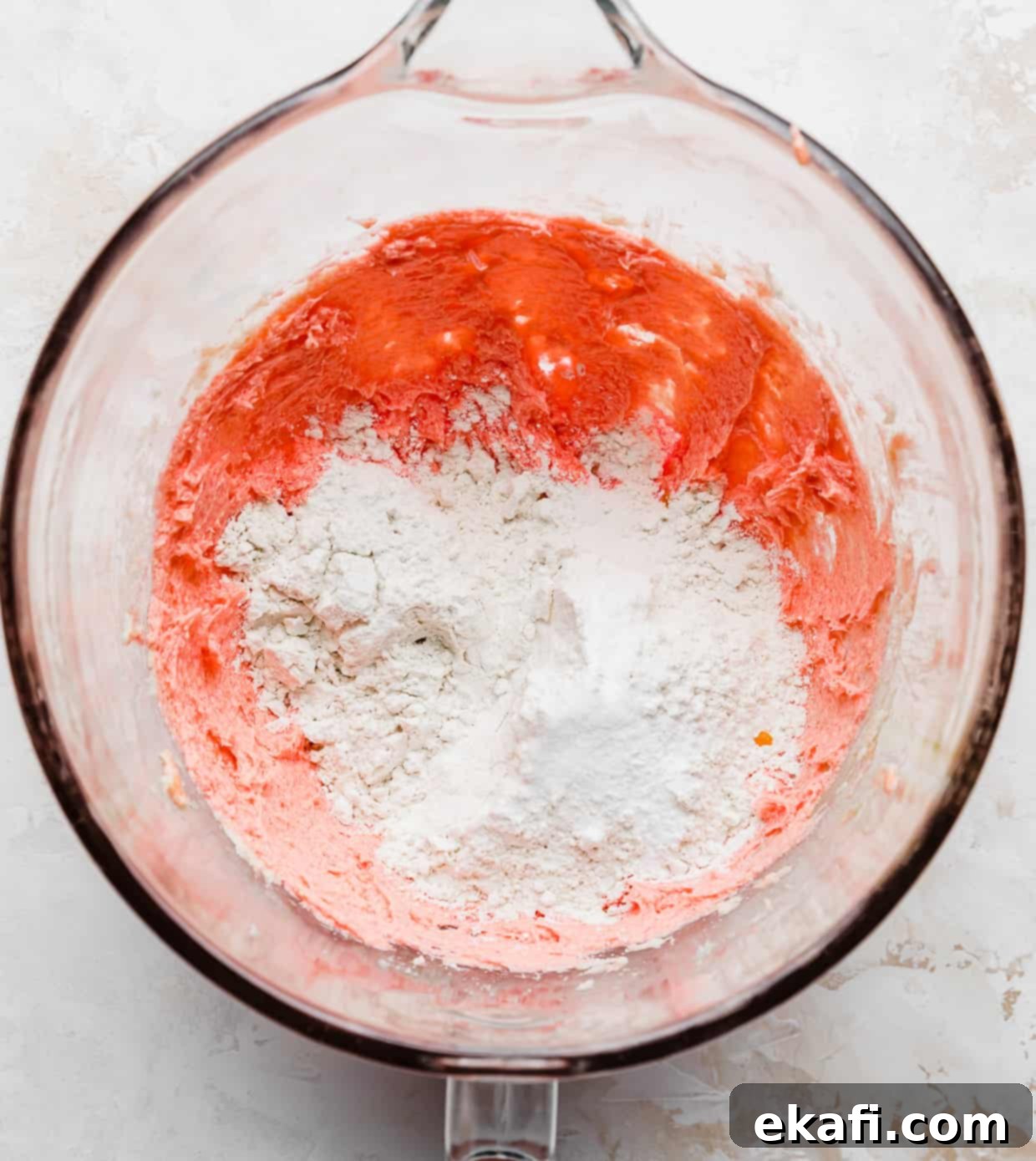 Blush Velvet Crumbl Delights 5 Flour overtop of pink cookie batter in a glass bowl.