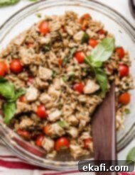 Perfect Summer Caprese Orzo 11 A Caprese Orzo Salad with fresh basil, chicken, tomatoes, and orzo in a glass bowl on a white background.