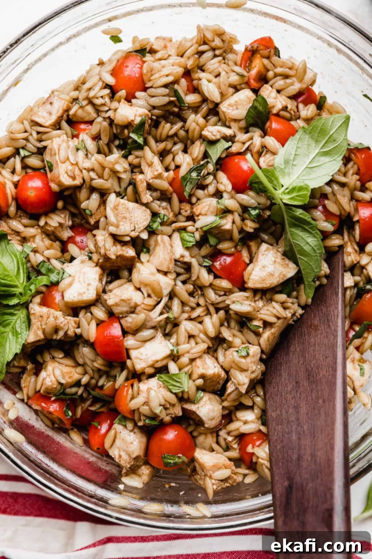 Perfect Summer Caprese Orzo 10 chicken orzo caprese salad in a glass bowl on a white background.