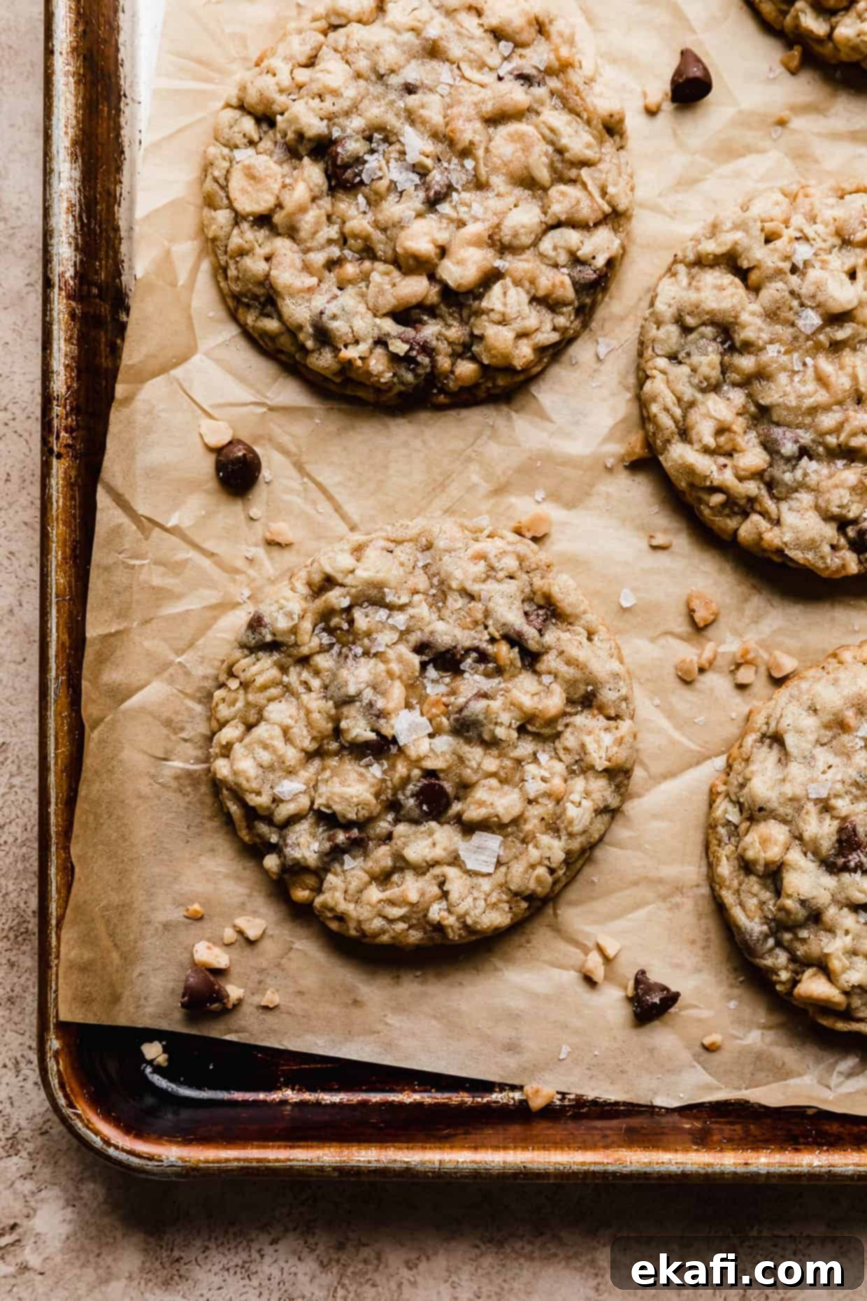 Mom's Secret Crumbl Cookie 2 A Mom's Recipe Crumbl Cookie copycat recipe on a brown baking sheet, showcasing its thick, chewy texture and visible mix-ins like chocolate chips, peanut butter chips, oats, and toffee.