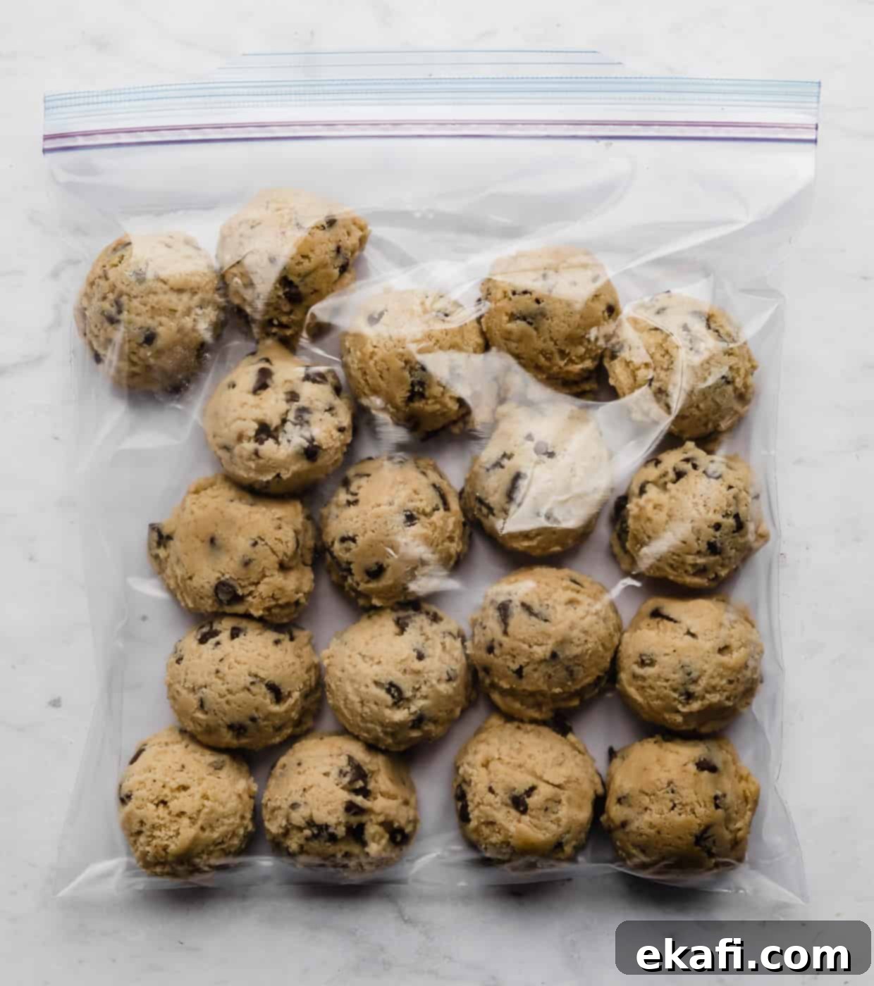 Freeze Cookie Dough for Instant Treats 7 Chocolate chip cookie dough balls in a ziplock bag on a white background.
