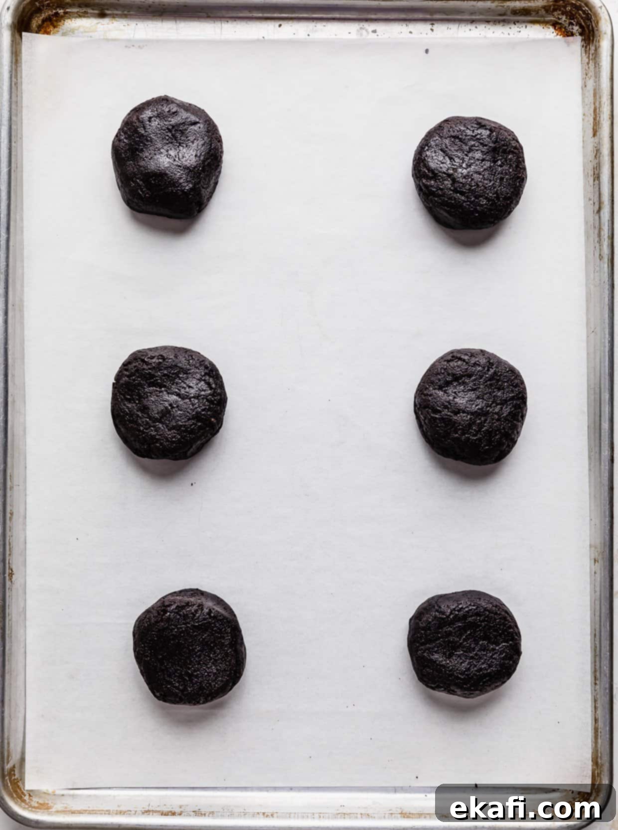 Crumbl Oreo Birthday Cake Cookie Delight 6 Six Oreo Birthday Cake Cookie dough balls on a white parchment paper.