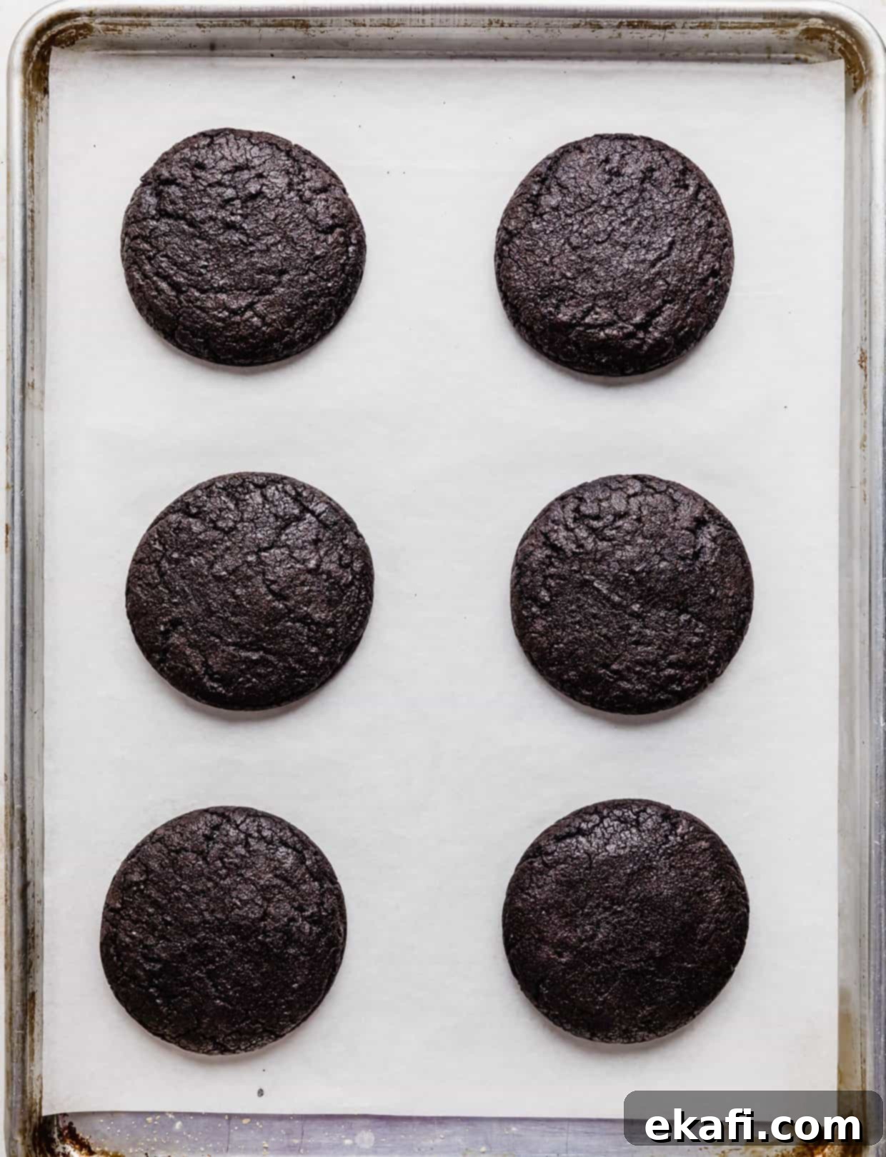 Crumbl Oreo Birthday Cake Cookie Delight 7 Six baked Crumbl sized Oreo Birthday Cake Cookies on a white parchment lined baking sheet.