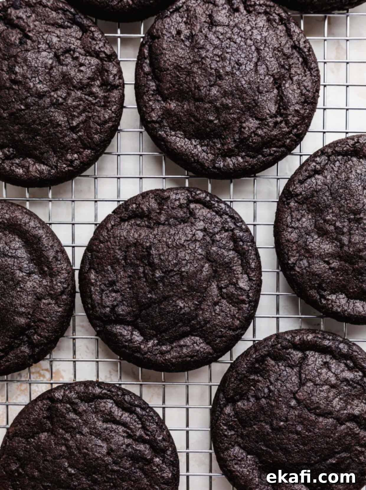 Crumbl Oreo Birthday Cake Cookie Delight 8 Baked dark Oreo cookies on a wire cooling rack.