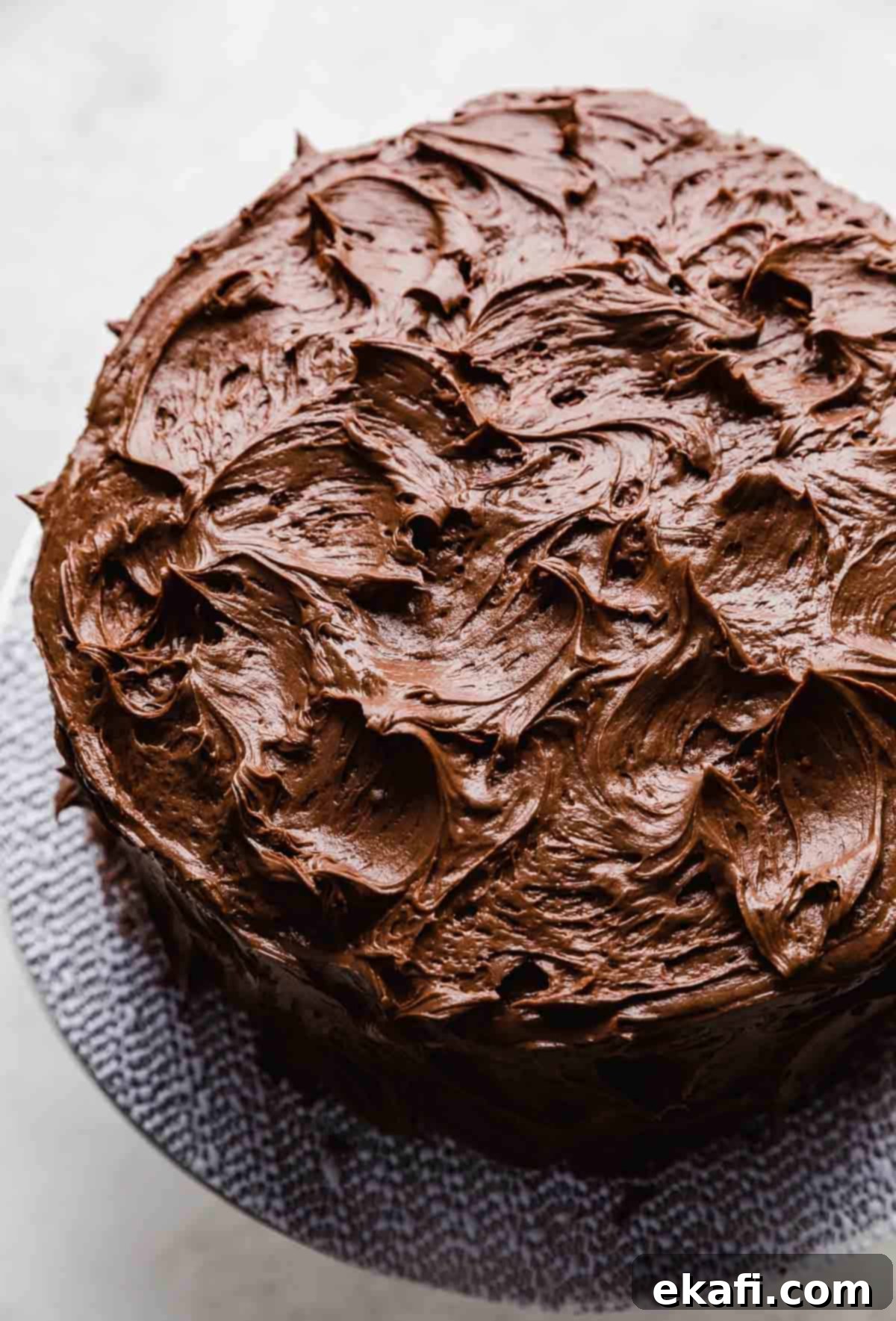 Velvet Chocolate Cream Cheese Cake 7 A chocolate cream cheese frosted chocolate cake on a cake stand against a white background.