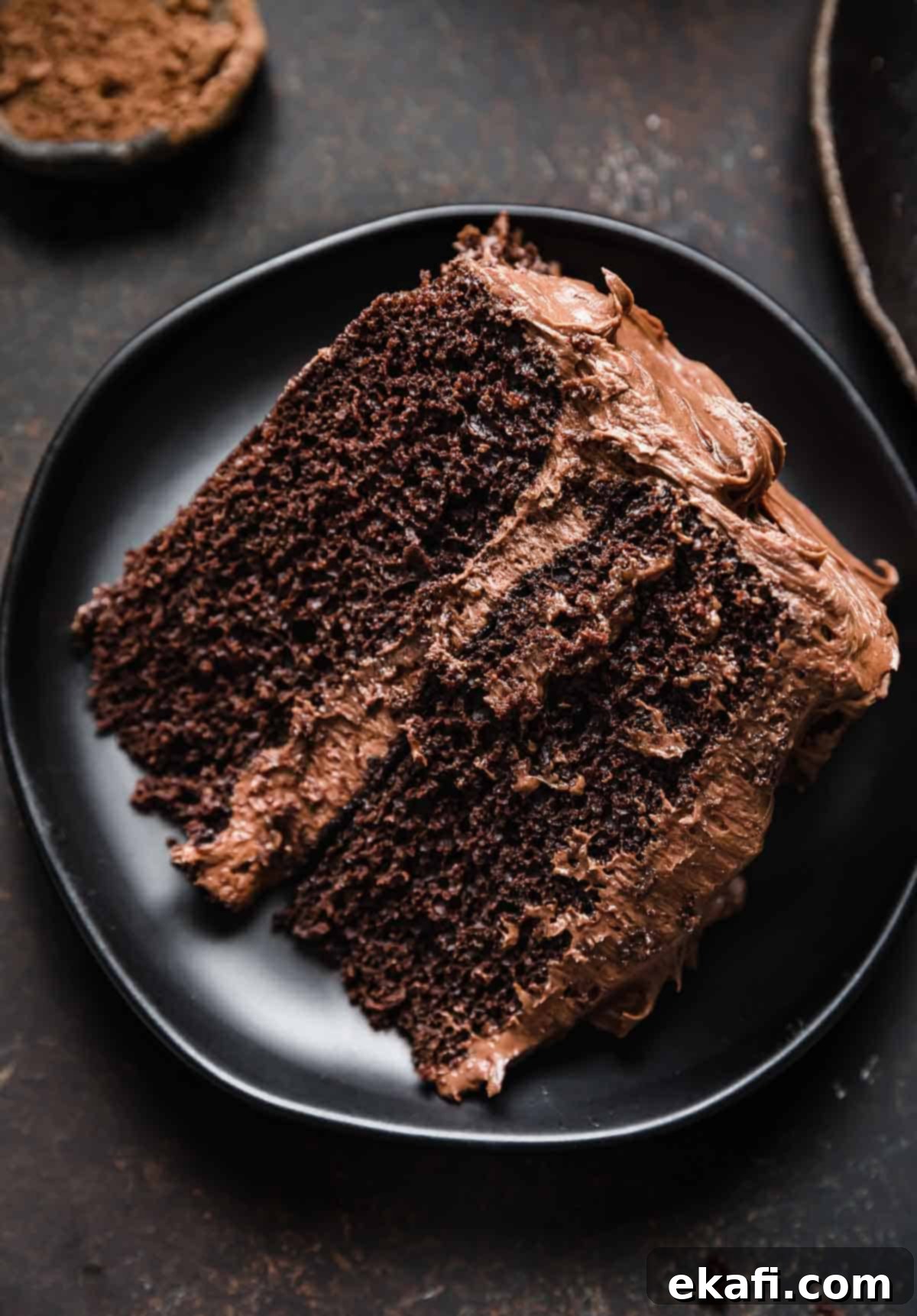 Velvet Chocolate Cream Cheese Cake 9 Two layer chocolate cake with a decadent chocolate frosting, on a black round plate.