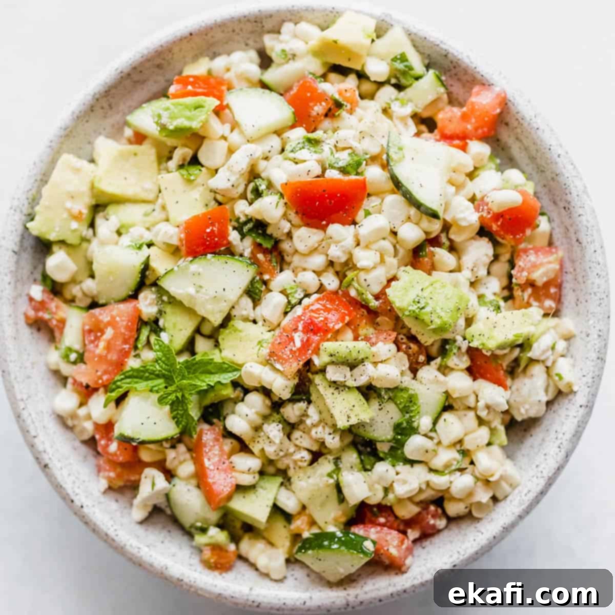 Creamy Zesty Corn Avocado Feta Salad 2 Feta Corn Salad in a bowl on a white background, showcasing fresh corn, avocado, tomatoes, and feta cheese.