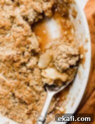 Quick & Easy Apple Crisp 16 A serving spoon scooping out homemade apple crisp from a white baking dish.