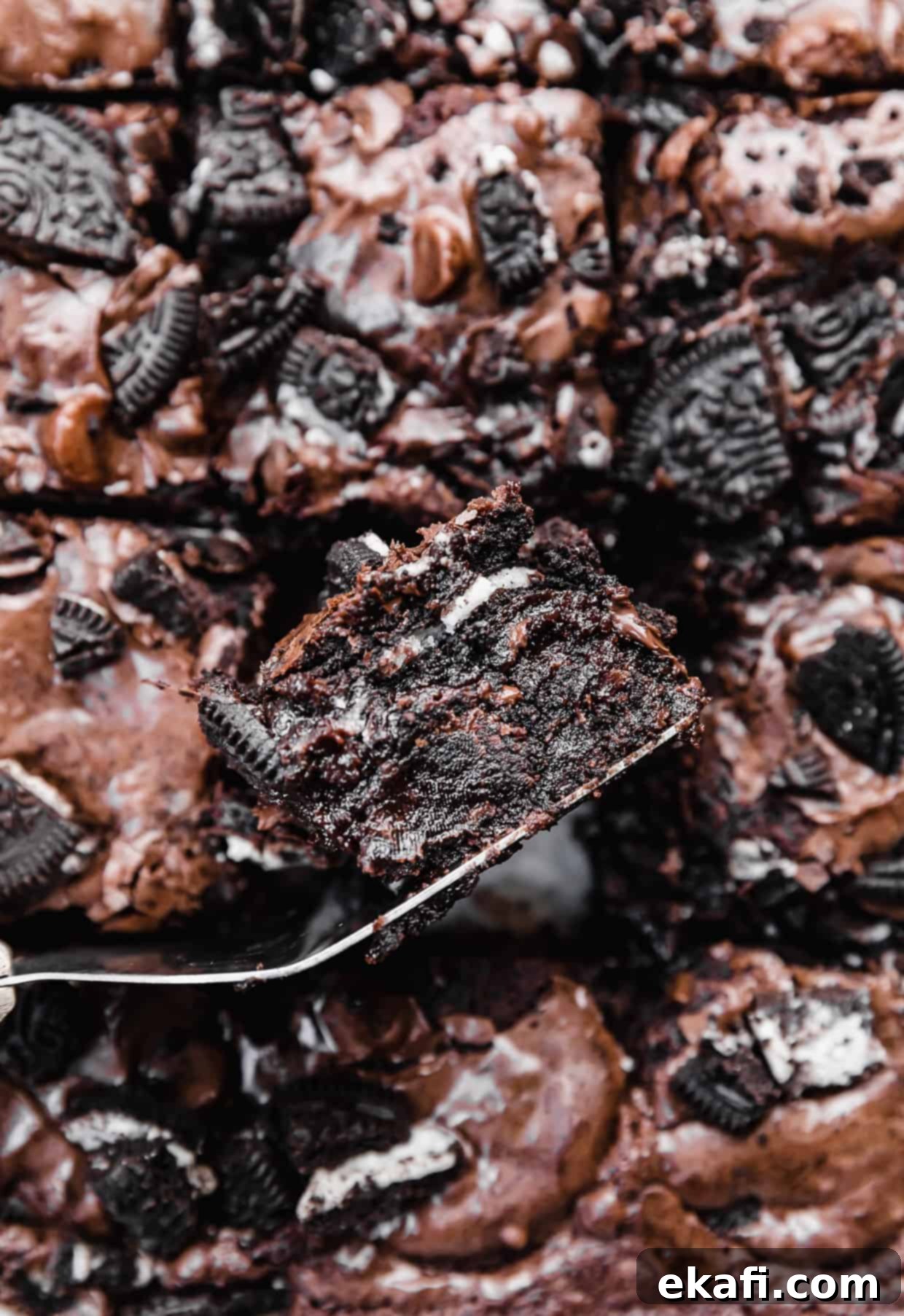 Ultimate Oreo Fudge Brownies 11 A fudgy Oreo brownie in a pan, tilted sideways to show the Oreo inside the brownie.