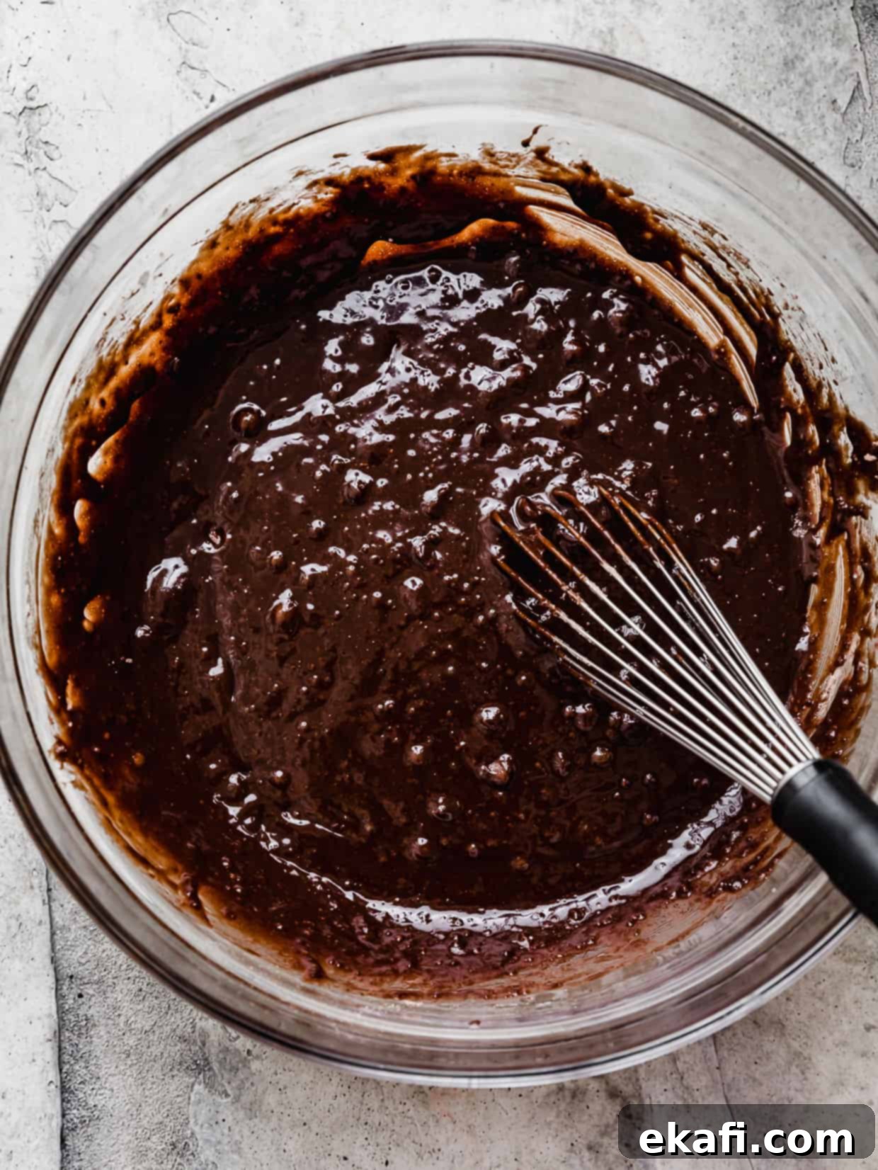Ultimate Oreo Fudge Brownies 5 A whisk mixing brownie batter in a glass bowl.