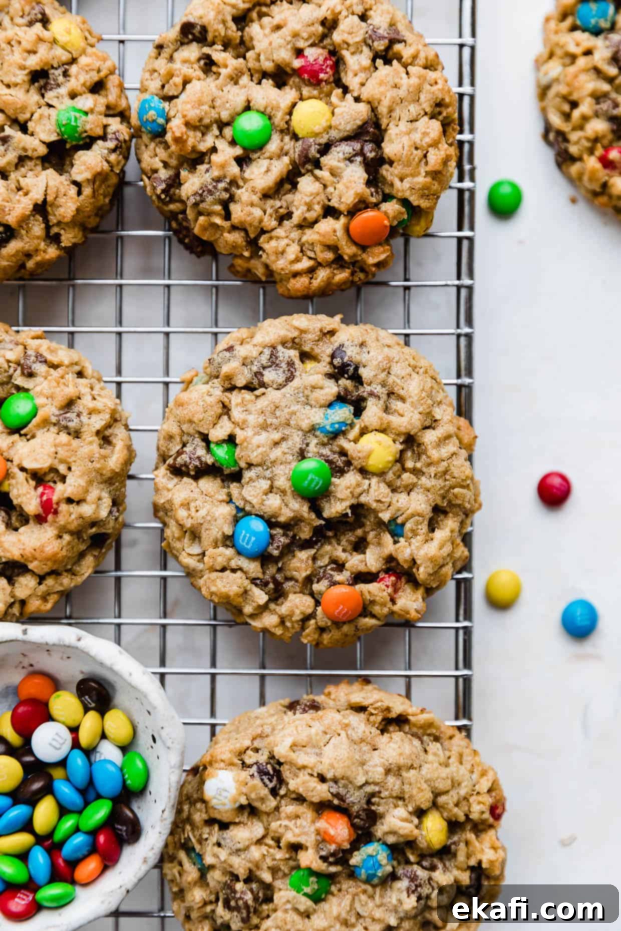 Loaded Chewy Cookies 2 Soft & Chewy Monster Cookies filled with mini M&M's, displayed beautifully on a wire cooling rack against a warm background.