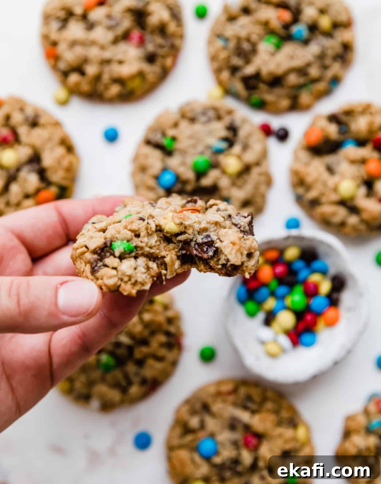 Loaded Chewy Cookies 7 A hand holding a delicious monster cookie with a bite taken out, revealing its soft interior packed with oats, chocolate, and M&M's.