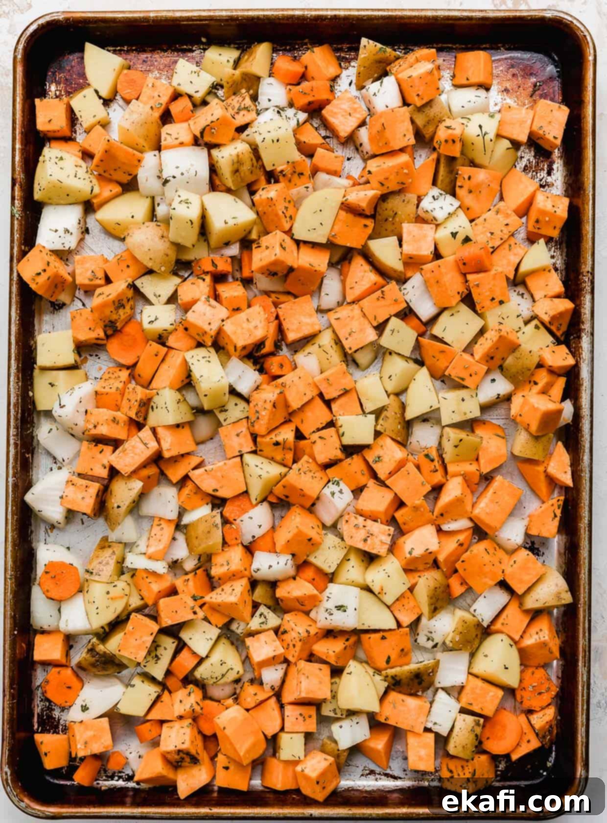 Easy Sheet Pan Root Roast 4 Root vegetables cut into chunks, on a baking sheet.