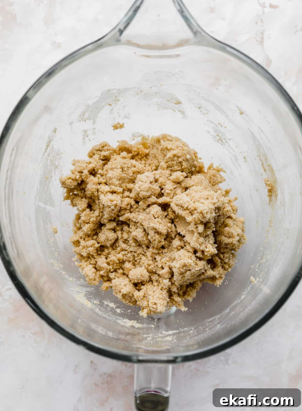 Crumbl Καλαμποκένιο Μπισκότο 4 Ζύμη για cornbread cookie σε ένα γυάλινο μπολ σε λευκό φόντο, έτοιμη για ψήσιμο.