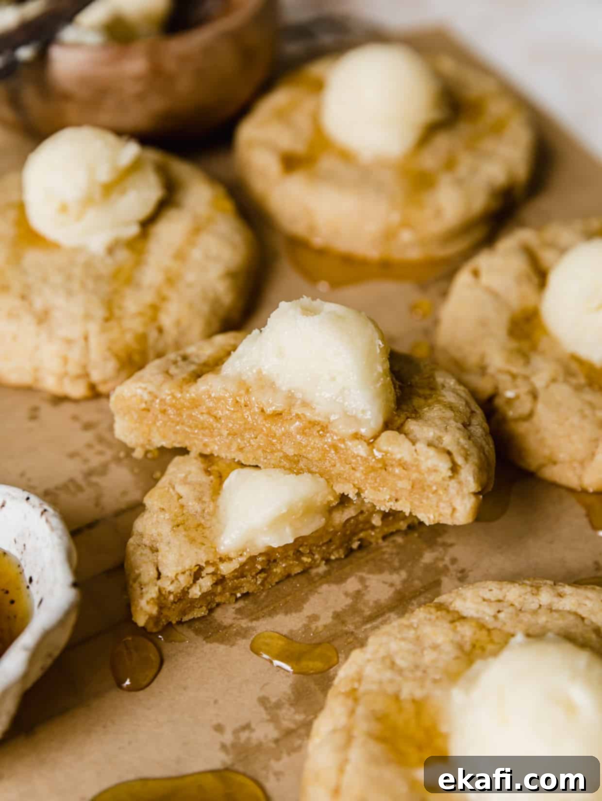 Crumbl Καλαμποκένιο Μπισκότο 9 Ένα cornbread cookie με επικάλυψη μελιού και βουτυρόκρεμα, κομμένο στη μέση, σε καφέ αντικολλητικό χαρτί, αποκαλύπτοντας την υφή του.