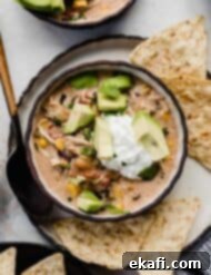 Dreamy Cream Cheese Chicken Chili 8 Sour cream and avocado on top of a bowl filled with cream cheese chicken chili recipe.