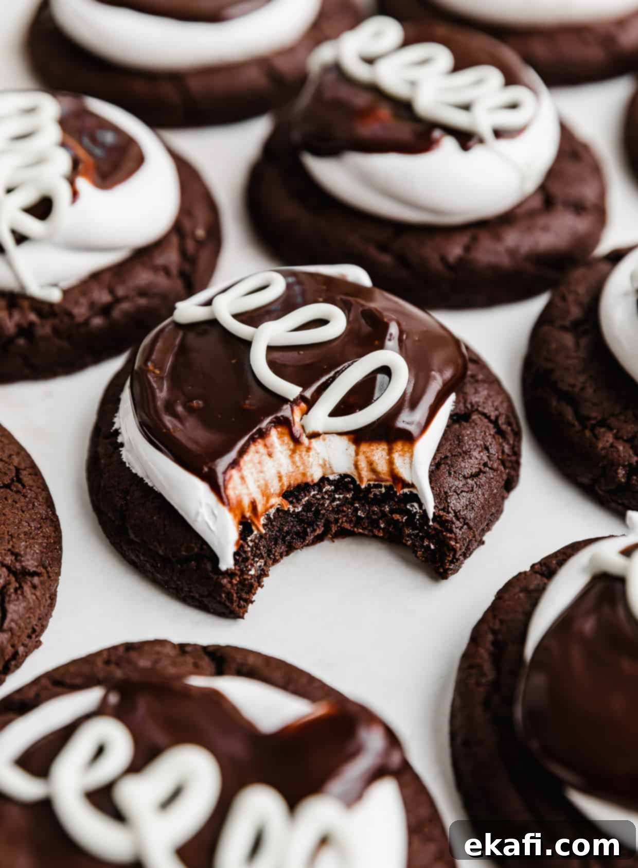 Hostess Cupcake Cookies 2 A delicious Hostess Cupcake Cookie with a bite taken out of it, showcasing the layers of rich chocolate cookie, fluffy marshmallow meringue, and smooth chocolate ganache, resting on a clean white background.