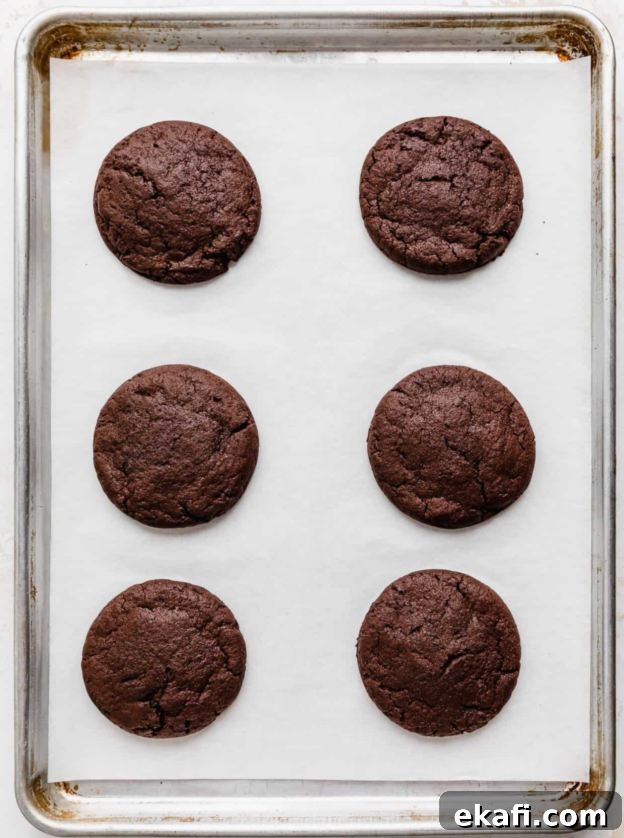 Hostess Cupcake Cookies 5 Six freshly baked chocolate cookies, with slightly crackled edges and soft centers, cooling on a white parchment paper lined baking sheet.