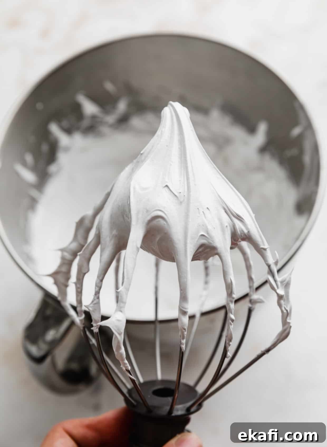Hostess Cupcake Cookies 6 A whisk coated in fluffy, perfectly whipped marshmallow meringue frosting, demonstrating its stiff peak consistency.
