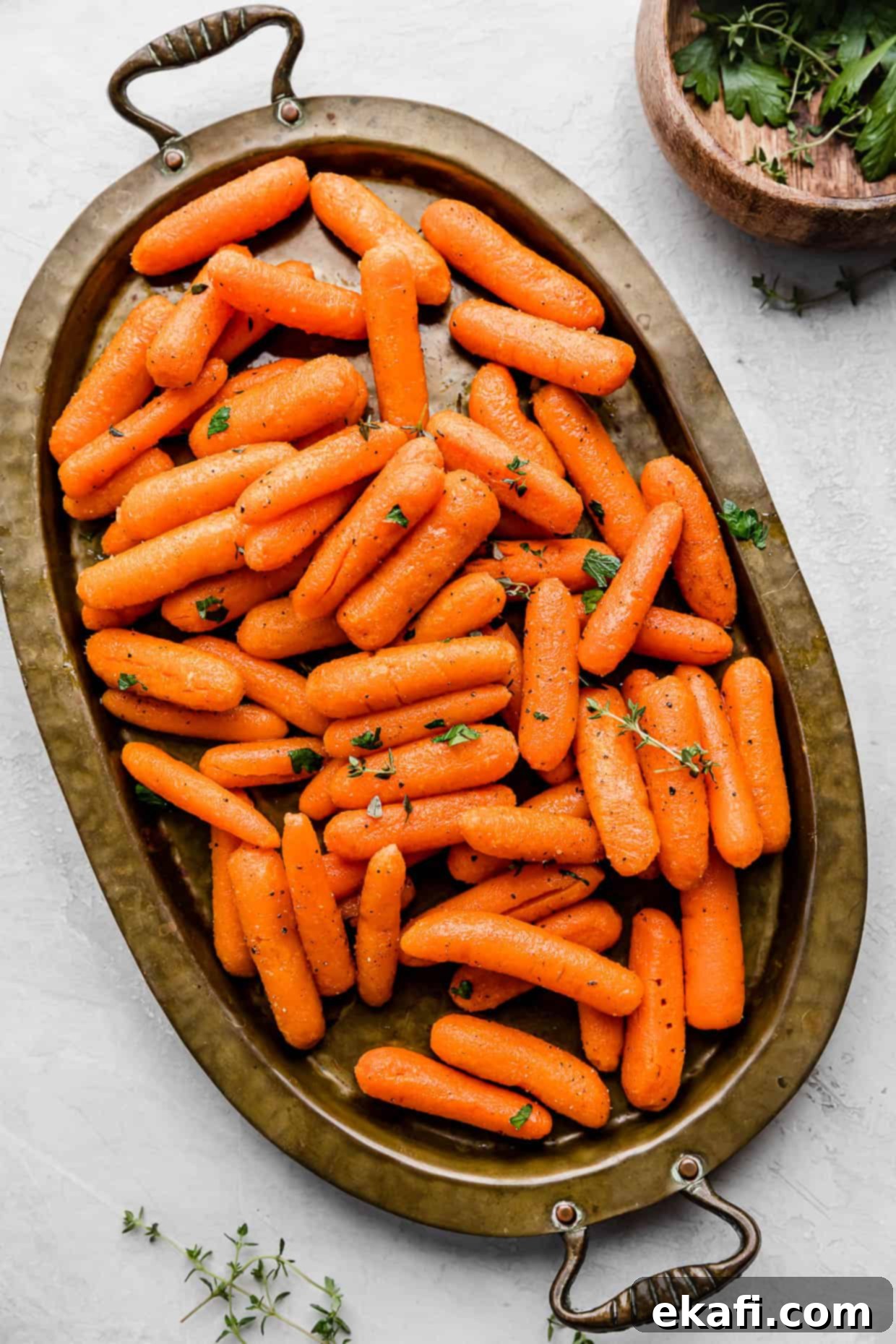 Caramelized Baby Carrots 7 Roasted Baby Carrots on a bronze oval plate on a white background.