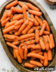 Caramelized Baby Carrots 8 Roasted Baby Carrots topped with thyme and parsley on a bronze oval plate.