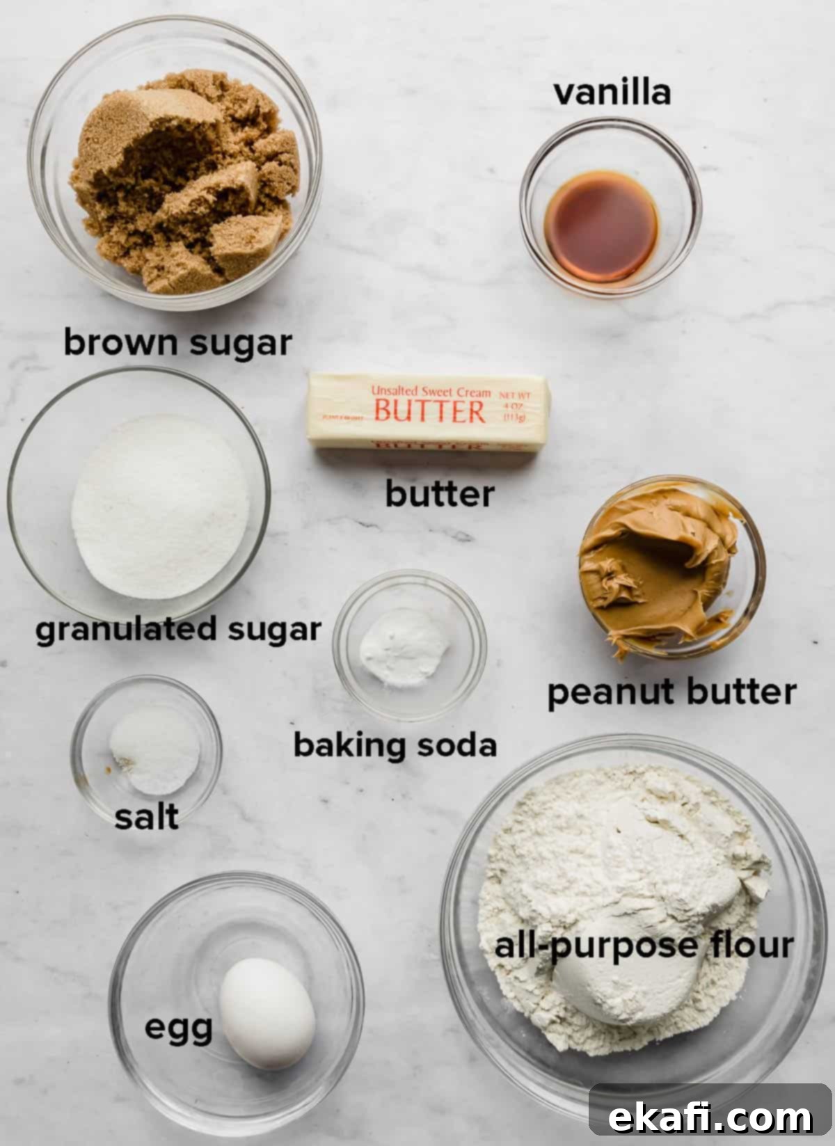 Crumbl Peanut Butter Blossoms 3 Crumbl Classic Peanut Butter Cookies ingredients placed in glass bowls on a white marble background.