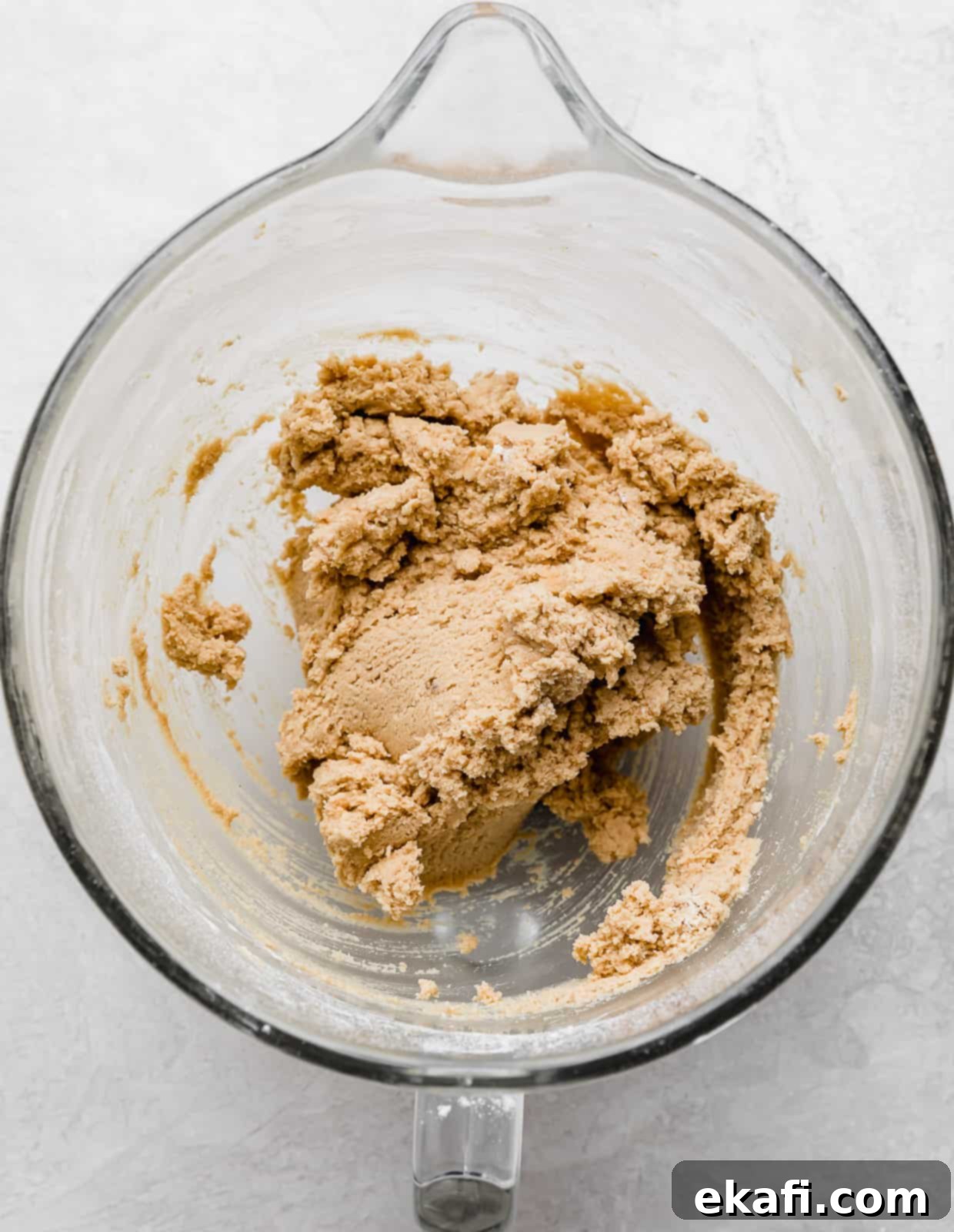 Crumbl Peanut Butter Blossoms 5 Crumbl Peanut Butter Blossom Cookie dough in a glass mixing bowl on a white background.