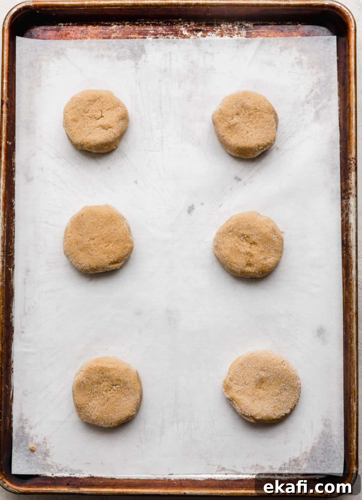 Crumbl Peanut Butter Blossoms 7 Six peanut butter cookie dough balls on a parchment lined baking sheet.