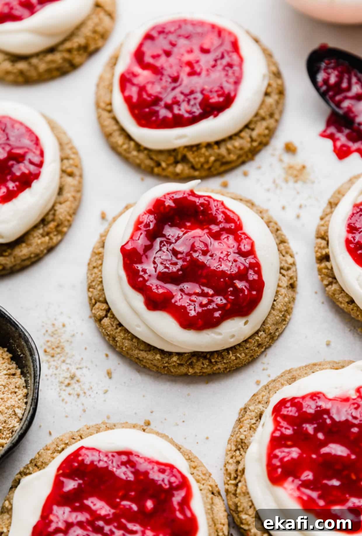 Creamy Raspberry Cheesecake Cookies 2 A Crumbl Raspberry Cheesecake Cookie made of a graham cracker cookie topped with a cream cheese frosting and raspberry sauce.