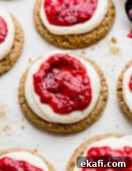 Creamy Raspberry Cheesecake Cookies 11 Raspberry Cheesecake Cookies: graham cracker cookie topped with cream cheese frosting, and raspberry sauce on a white background.