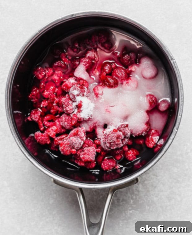 Creamy Raspberry Cheesecake Cookies 4 A saucepan full of frozen raspberries, water, and sugar.