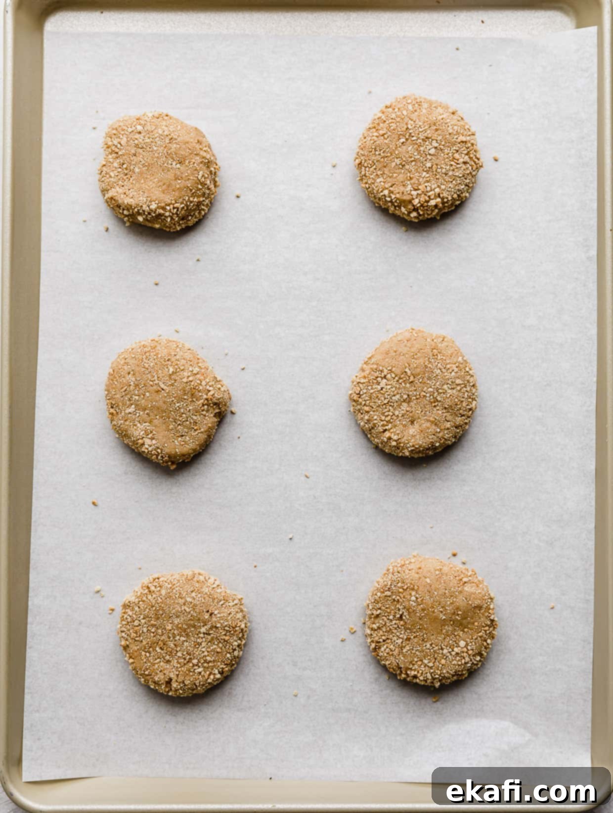 Creamy Raspberry Cheesecake Cookies 6 Six graham cracker cookie dough balls on a white parchment lined baking sheet.