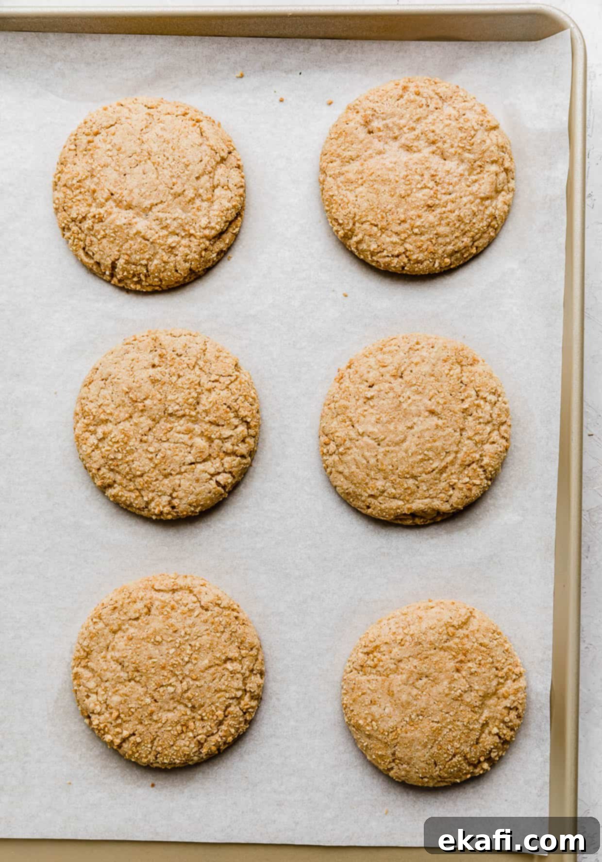 Creamy Raspberry Cheesecake Cookies 7 Six baked graham cracker cookies on a baking sheet, used to make Crumbl Raspberry Cheesecake Cookies.