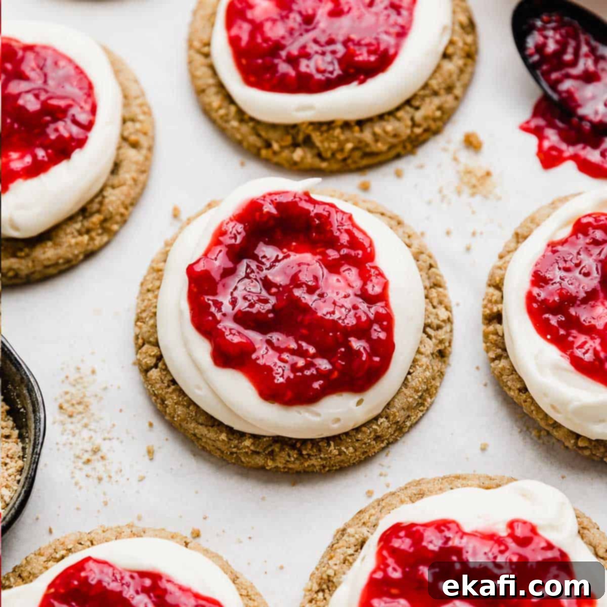 Creamy Raspberry Cheesecake Cookies 9 Raspberry Cheesecake Cookies: graham cracker cookie topped with cream cheese frosting, and raspberry sauce on a white background.