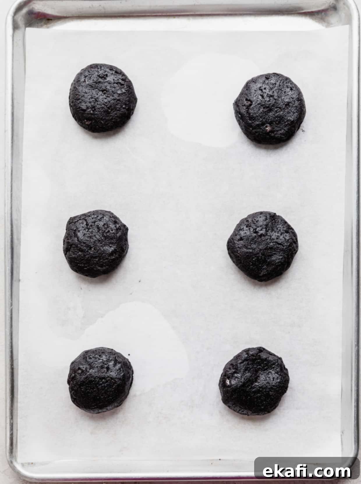 Decadent French Silk Pie Cookies 4 Six black Oreo cookie dough balls on a white parchment paper.