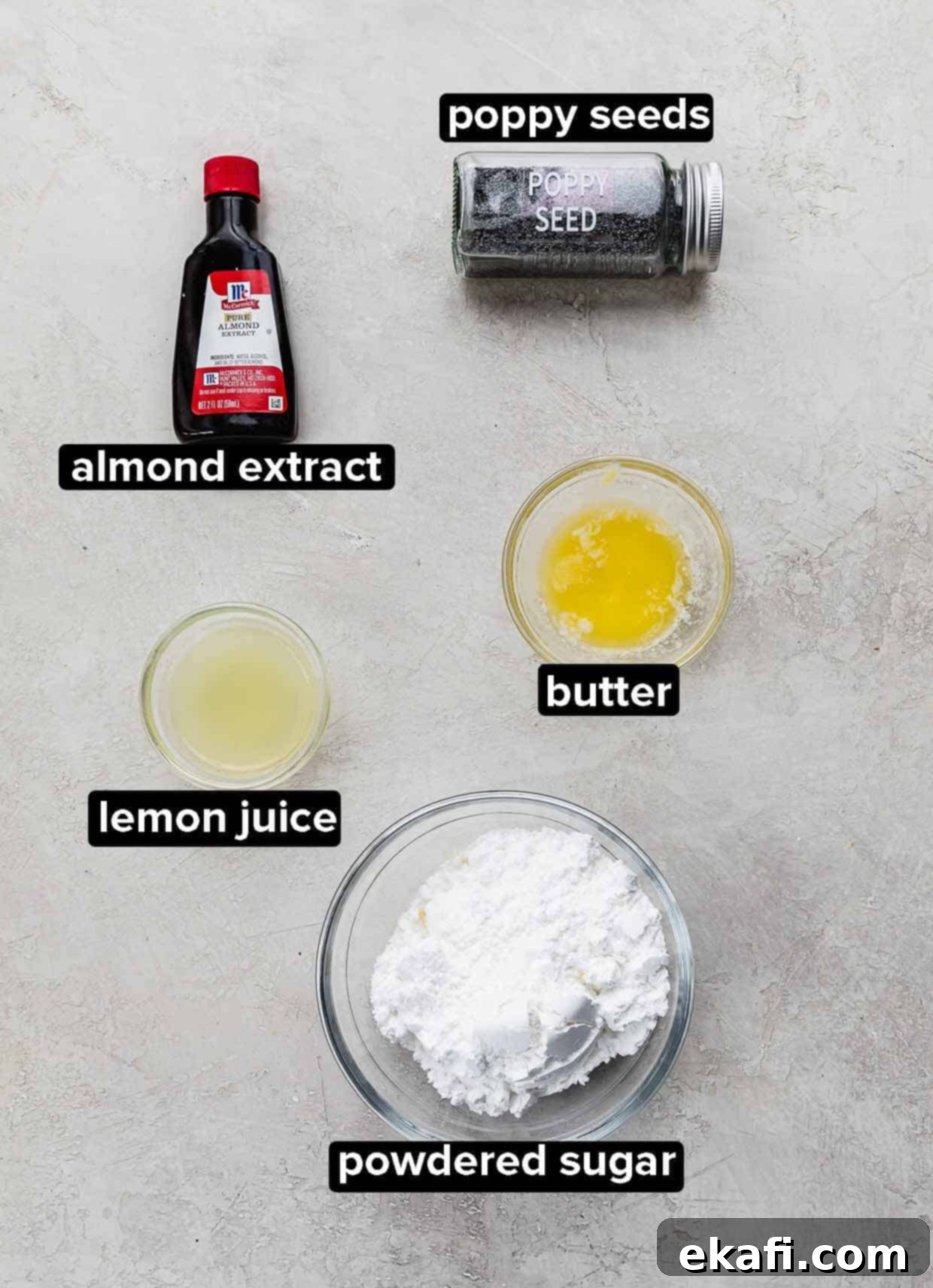 Zesty Lemon Poppy Seed Delights 4 Almond extract, powdered sugar, lemon juice, butter, and poppy seeds on a gray background, used to make glaze for Lemon Poppy Seed Cookies.