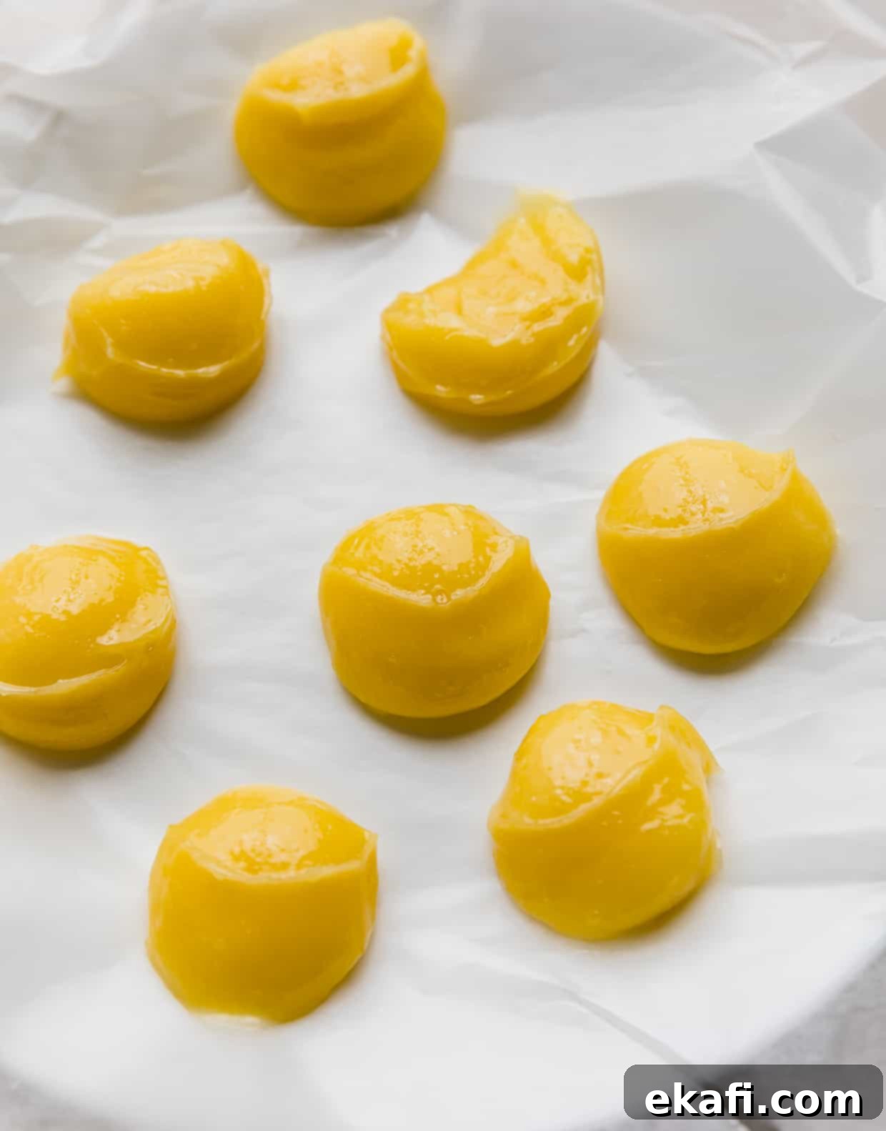 Zesty Lemon Poppy Seed Delights 5 Lemon curd dollops on a wax paper lined white plate.