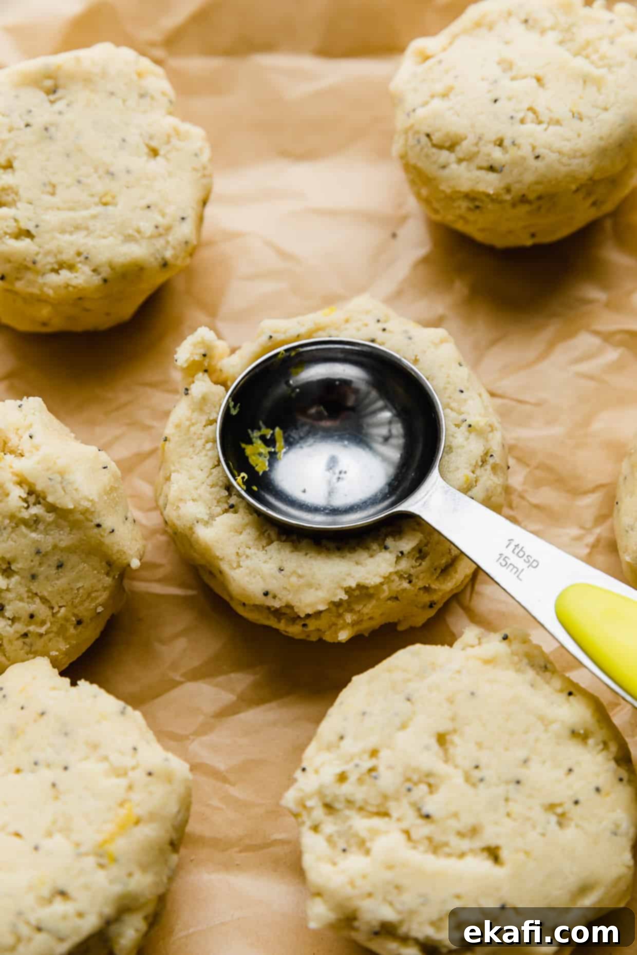 Zesty Lemon Poppy Seed Delights 7 A tablespoon pressing into lemon poppy seed cookie dough.