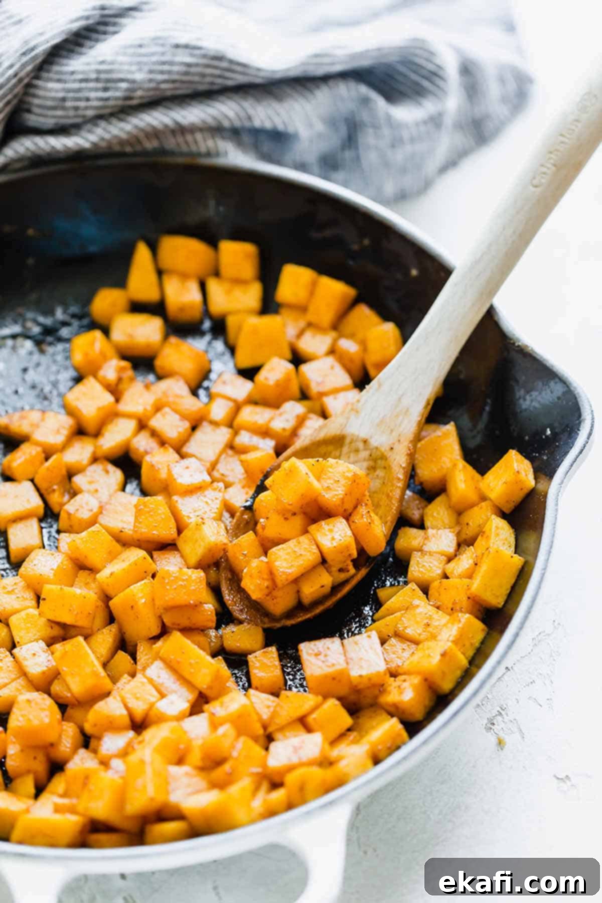 Roasted Butternut Squash and Kale 4 Cubed, cooked butternut squash in a white skillet, seasoned and tender.