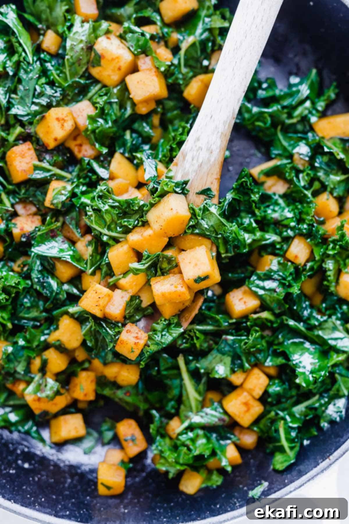Roasted Butternut Squash and Kale 6 Butternut Squash and Kale mixed together in a skillet, with a wooden spoon scooping up some of the vibrant dish.